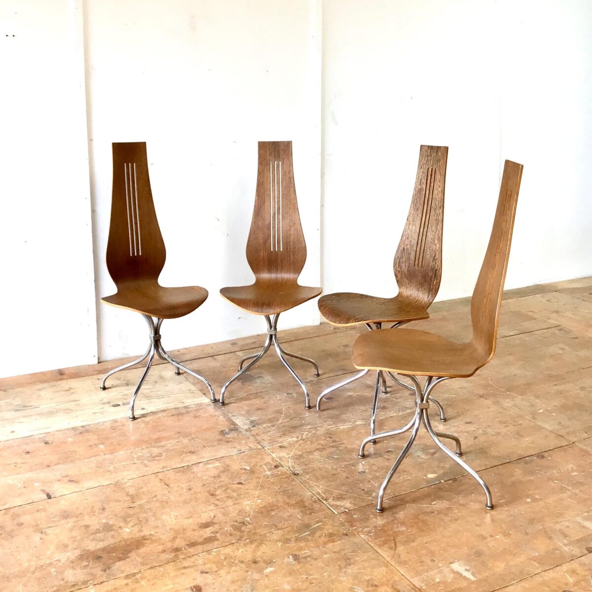 Midcentury Esszimmer Stühle von Theo Häberlin aus den 70er Jahren. Sitzhöhe 45cm gesamt Höhe ca. 106cm. Die Formsperrholz Sitzschale, mit hohem Rücken, ist angenehm zwischen den Schulterblättern. Diese Stühle heben sich vorallem durch die Höhe von anderen Stühlen ab. Die Lehne überragt deutlich die Höhe einer Tischkante. Das Metall Untergestell ist verchromt, stabil und hochwertig ausgeführt. Der kleine Metall Würfel, durch den die Stuhlbeine verlaufen, erinnert mich an Art déco Möbel Elemente. Einer der Stühle unterscheidet sich deutlich durch die lebhafte Holzmaserung. 