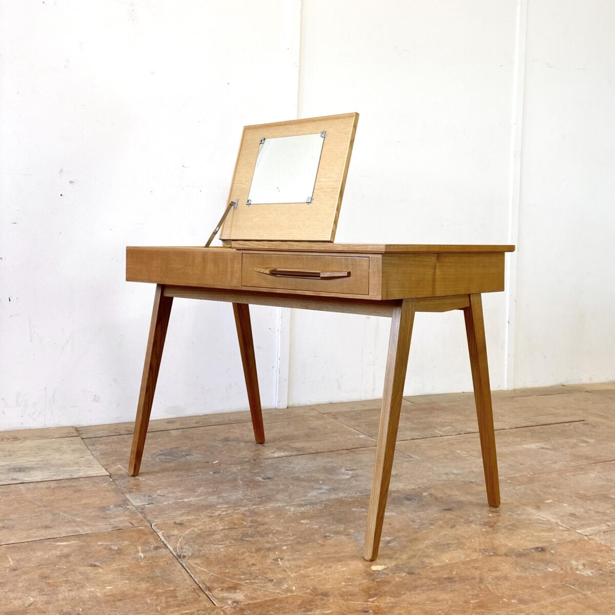 Deuxieme.shop swissdesign Desk. 50er Jahre Schreibtisch aus Esche von Corta Multiform. 105x60cm Höhe 74cm. Der Tisch hat eine Schublade mit Kunstleder griff, eine Klappe mit Stauraum und Schminkspiegel. Der Spiegel ist etwas beschlagen, ansonsten ist der Schreibtisch in gepflegtem guten Zustand.