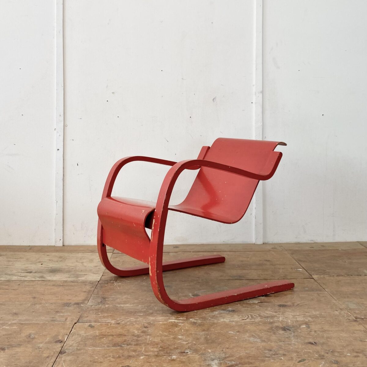 Deuxieme.shop Alvar Aalto Freischwinger Sessel. Modell 31 Birke Formsperrholz. Der Sessel ist etwas asymmetrisch (verzogen) was bei älteren Modellen öfters so ist. Im Bild 4 gut zu sehen. Die rote Farbe ist etwas abgewetzt, und mehrere Farbabplatzer an diversen Stellen. 