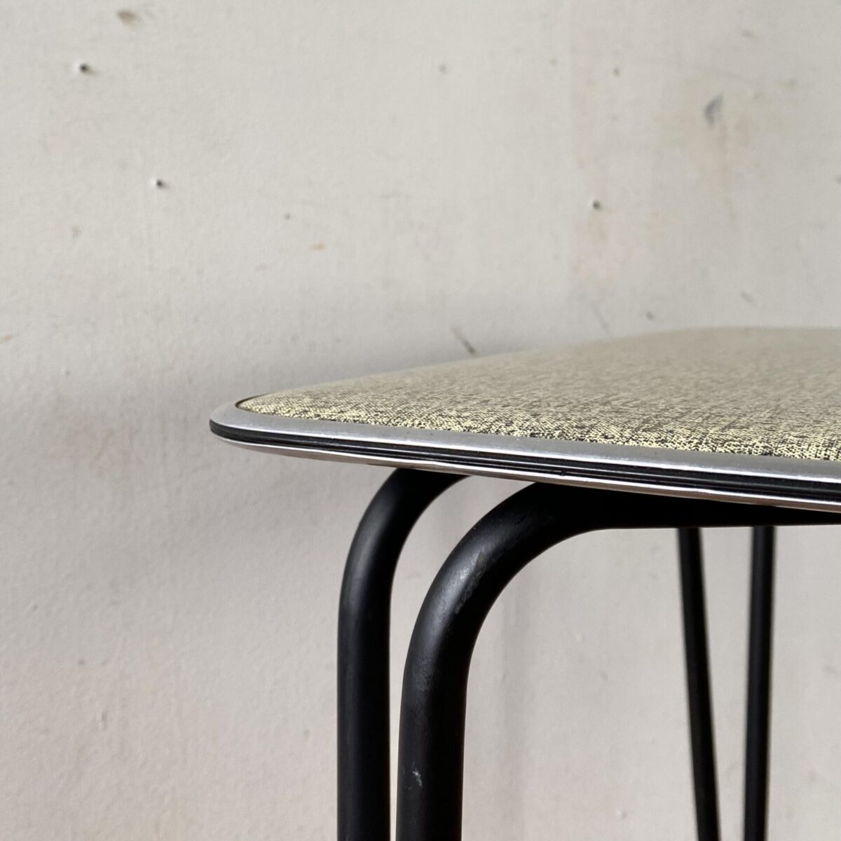 Deuxieme.shop 60er Jahre Tisch. Kleiner kompakter Küchentisch mit schwarzen konischen Stahlbeinen. 66x66cm Höhe 67cm. Das Werzalit Tischblatt ist grün-schwarz meliert, zur Kante hin verjüngt, und mit einer Aluminiumkante eingefasst. Der Tisch eignet sich auch als Gartentisch oder Balkontisch. Die Hairpin artigen Tischbeine sind schwarz lackiert und mit Gummifüssen bestückt. Die Tischkante, aus Alu, ziert ausserdem ein feines eingepresstes Kunststoff Filet. 