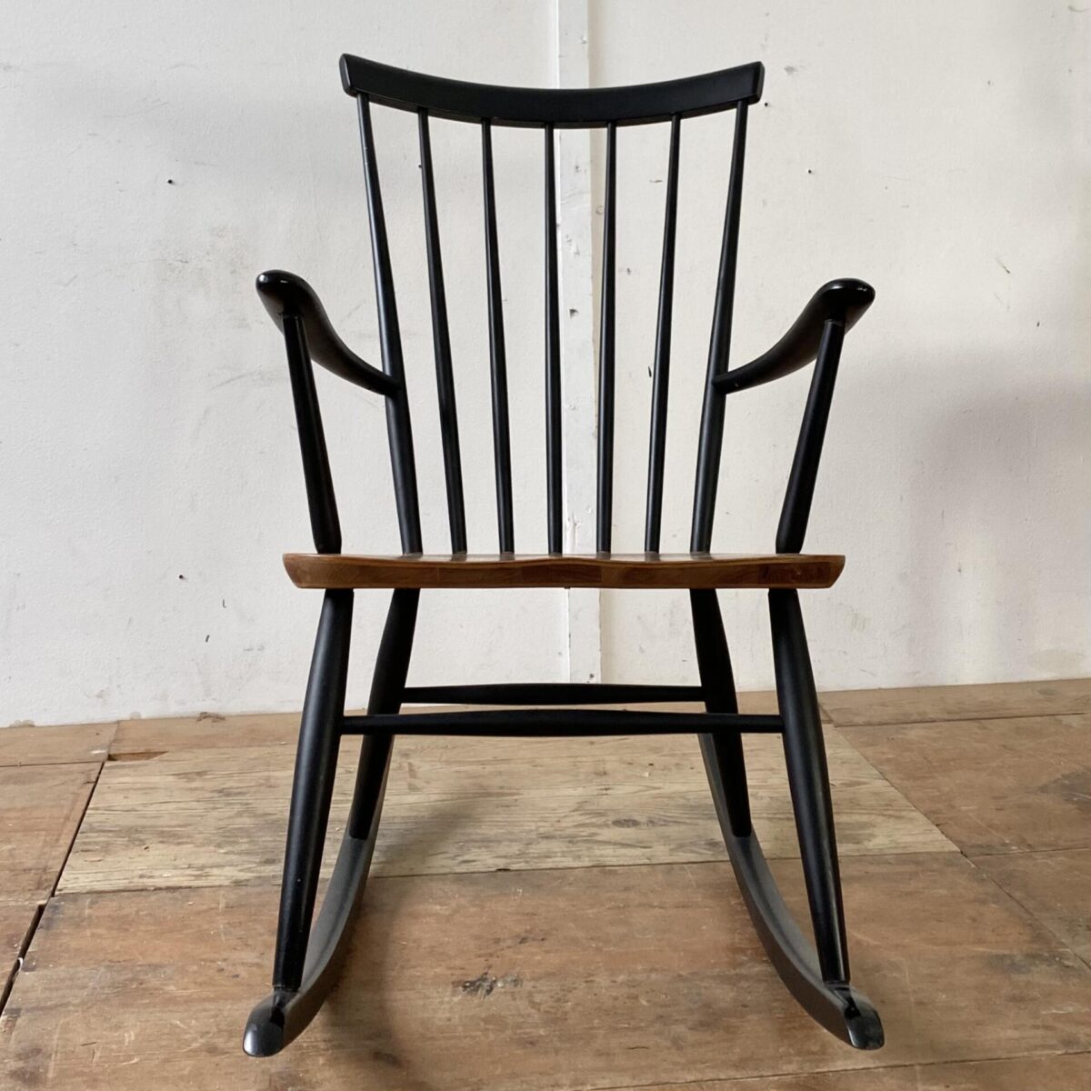 Deuxieme.shop Midcentury Teak Rocking Chair. Schaukelstuhl von Ronald Rainer aus den 50er Jahren. Der Sessel ist in stabilem guten Zustand. Die Sitzfläche ist mit Teakholz furniert, die übrigen Teile aus Buche Vollholz, schwarz lackiert, diverse kleinere Farb Abschürfungen. 