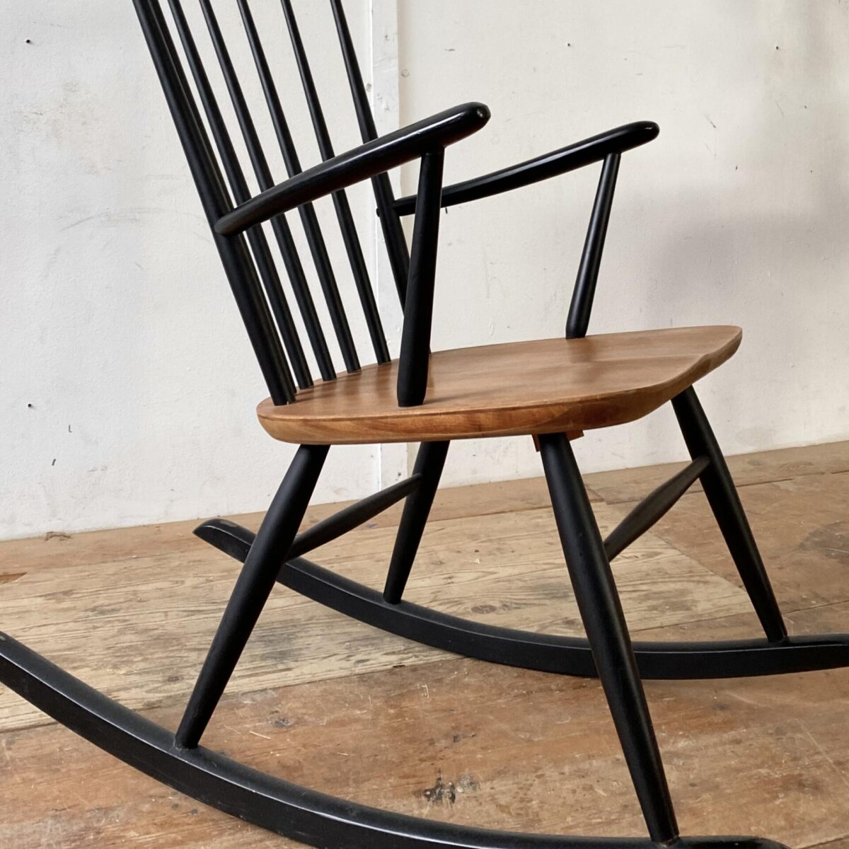 Deuxieme.shop Midcentury Teak Rocking Chair. Schaukelstuhl von Ronald Rainer aus den 50er Jahren. Der Sessel ist in stabilem guten Zustand. Die Sitzfläche ist mit Teakholz furniert, die übrigen Teile aus Buche Vollholz, schwarz lackiert, diverse kleinere Farb Abschürfungen. 