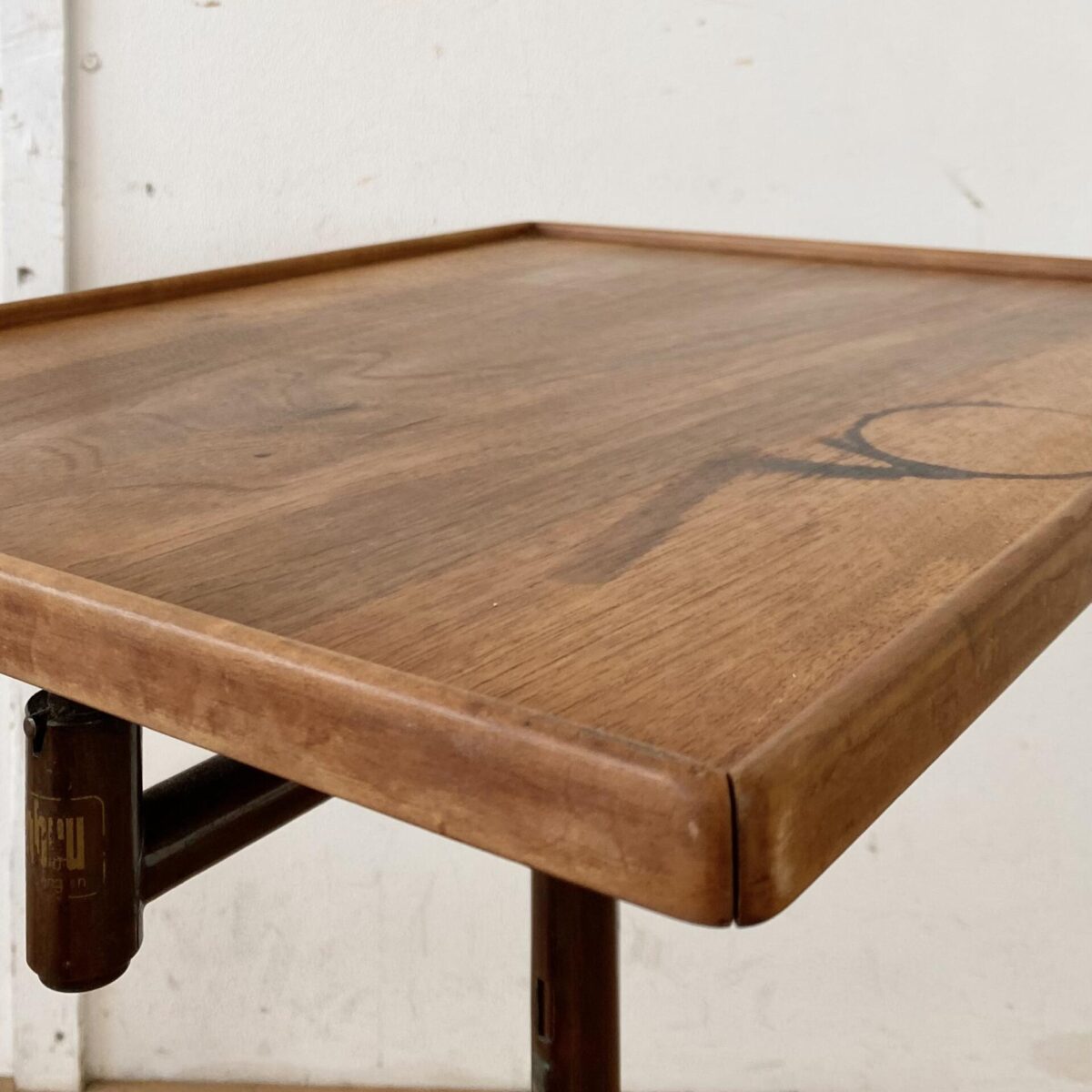 Deuxieme.shop Swiss designklassiker. Höhenverstellbarer Embru Tisch, von Georg Albert Ulysse Caruelle. Der Tisch ist höhenverstellbar von 70 bis 98cm. Die Hauptplatte ist Neigbar und misst 51.5x41.5cm. Das Metallgestell ist Kupferbrüniert, der eine fuss ist ausziehbar. Der Tisch kann vielseitig eingesetzt werden, als Betttisch, Sofa Beistelltisch, Notenständer oder als kleiner Arbeitstisch. Das Nussbaum furnierte Tischblatt hat eine kleine Luftblase bei genauer Betrachtung, ansonsten in schönem Vintage Zustand mit ein paar kleinen Wasserflecken und dem Tintenfass Ring. 